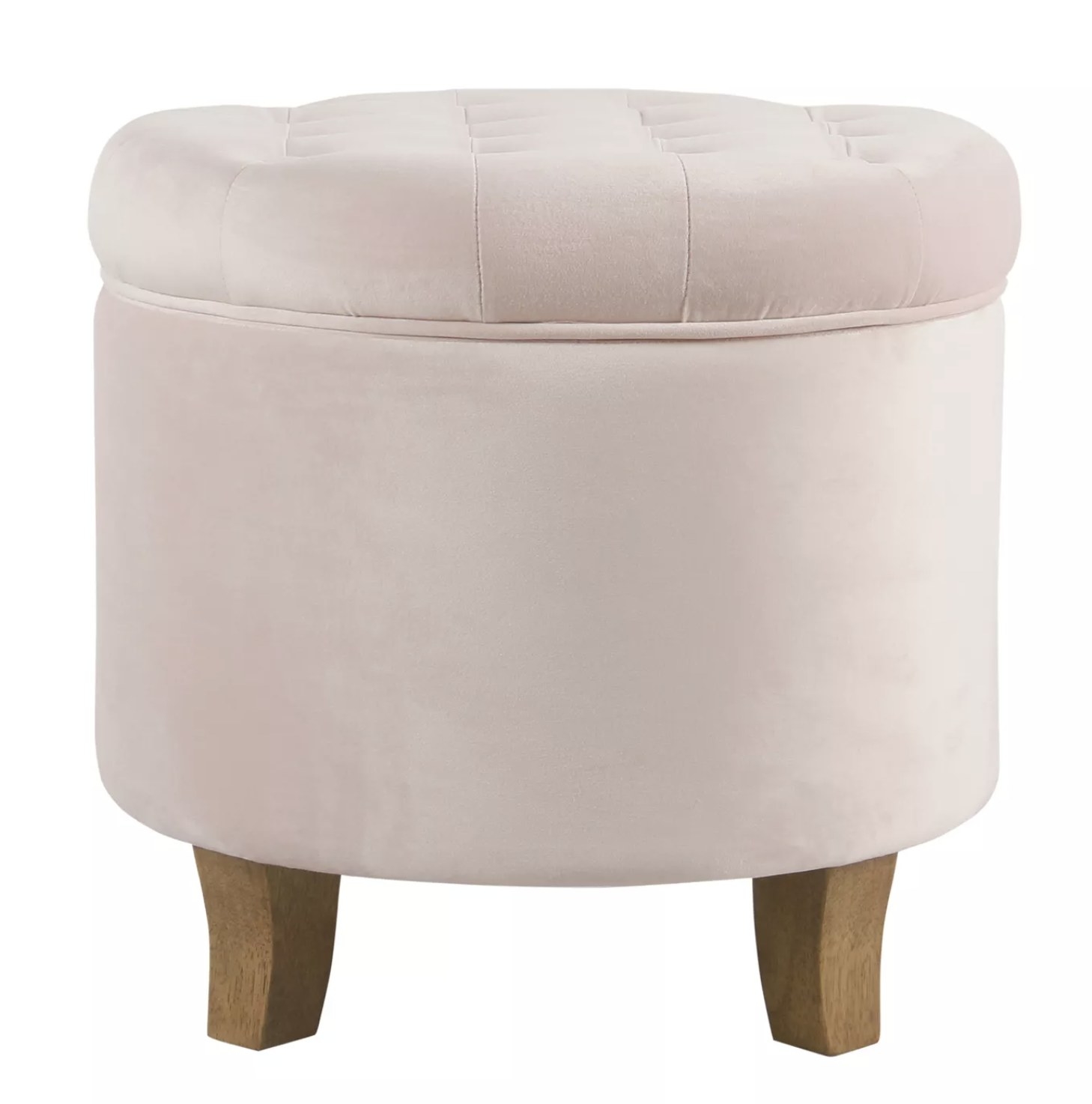 A velvet blush pink round storage ottoman with a tufted lid and wooden legs
