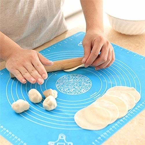 The silicone mat with different circular markings and a person rolling out a small flatbread using the mat&#x27;s measurements. 