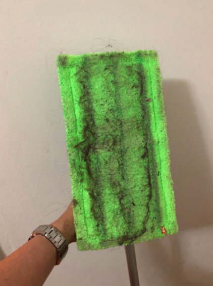 Reviewer holds dirty green microfiber mop pad in their hand