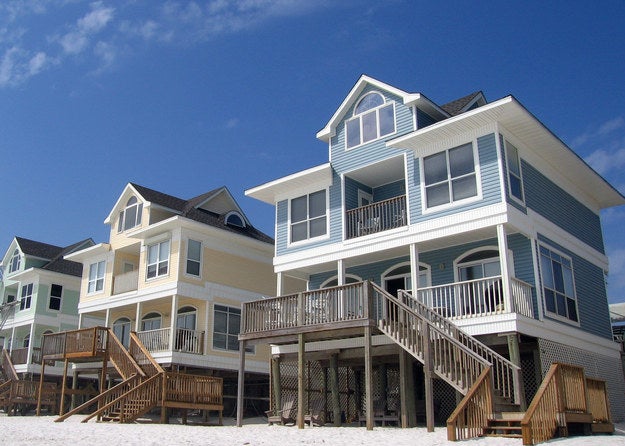 An upward shot of a row of beach houses on stilts out of the sand