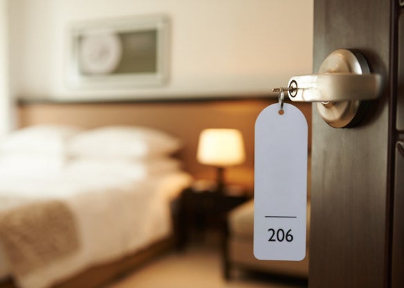 A key hangs from an open door to a hotel room in the blurry background