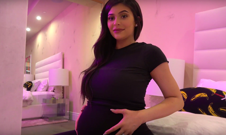 Kylie stands with hands on her pregnant belly