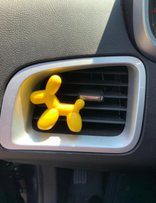 reviewer pic of a car vent with the yellow air freshener clipped onto it