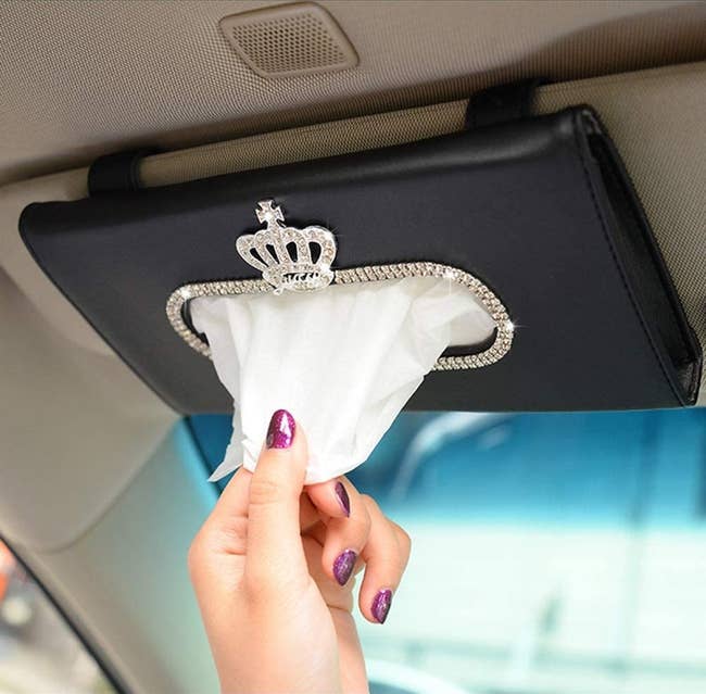 hand pulling tissues out of visor holder that has a rhinestone crown design on it