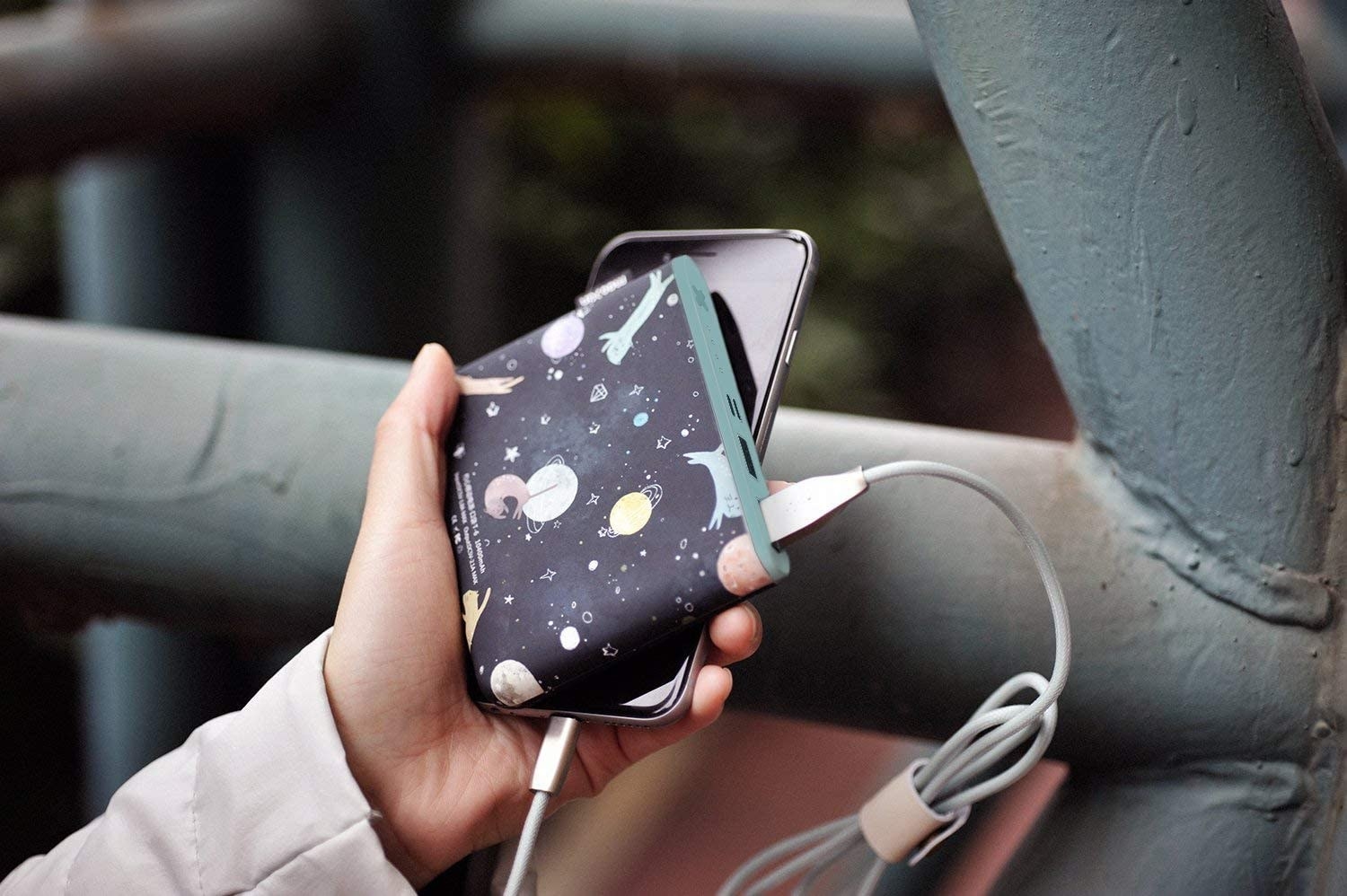 a hand holding a space-themed portable charger bank 