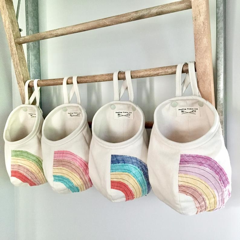 four rainbow pods of various colors hanging from a rack 