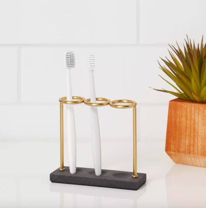 The toothbrush holder with three gold loops and black base