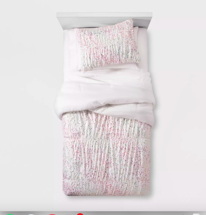 The white comforter covered with shimmery multi-colored dots on one side and plain white on the other, with matching pillowcases 