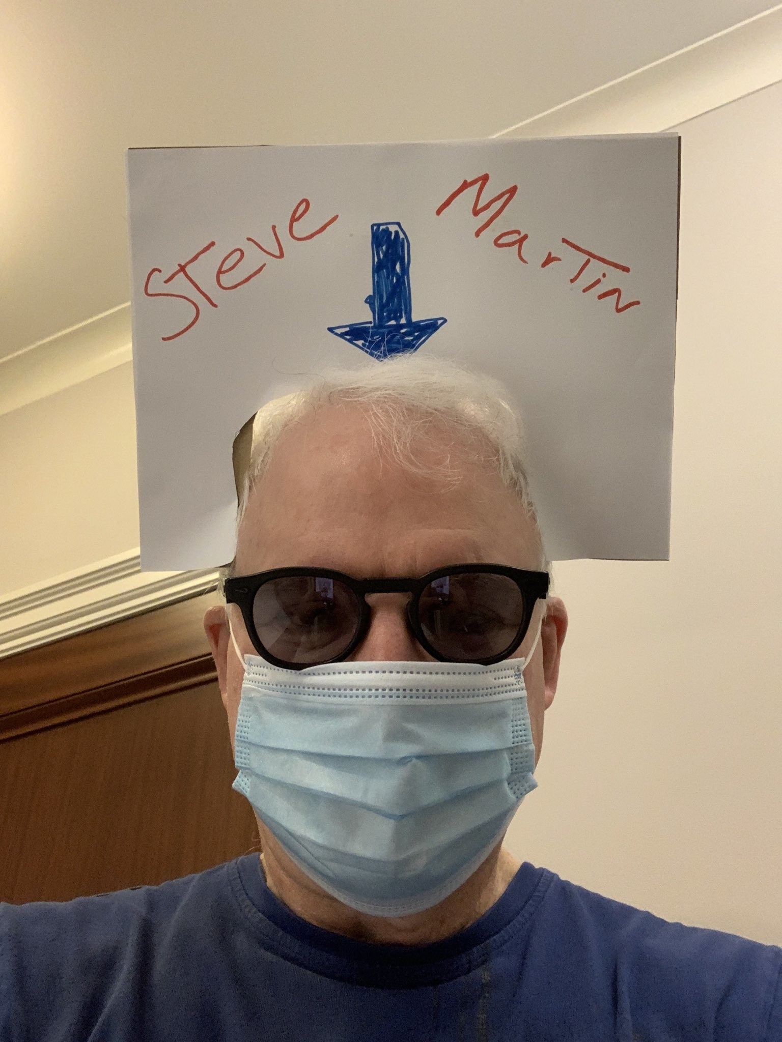 Steve wearing a cardboard sign around his head that says &quot;Steve Martin&quot; with an arrow pointing to his face