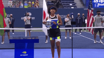 Naomi holds her third Grand Slam trophy as confetti strings falls from the sky