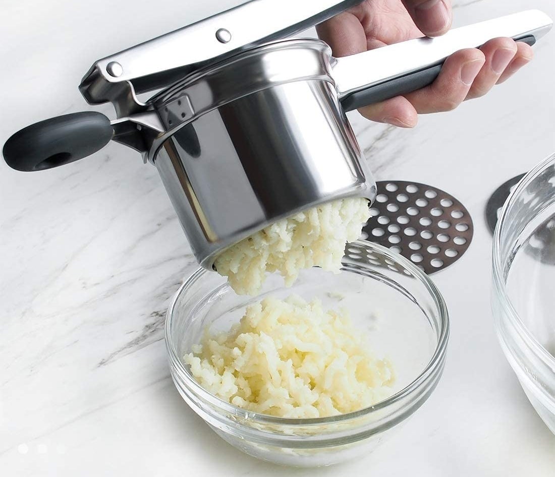 A potato ricer squeezes potatoes into a bowl