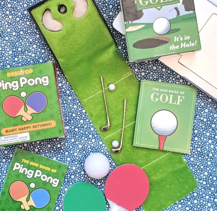 A mini golfing green with two clubs and two balls on it next to a computer