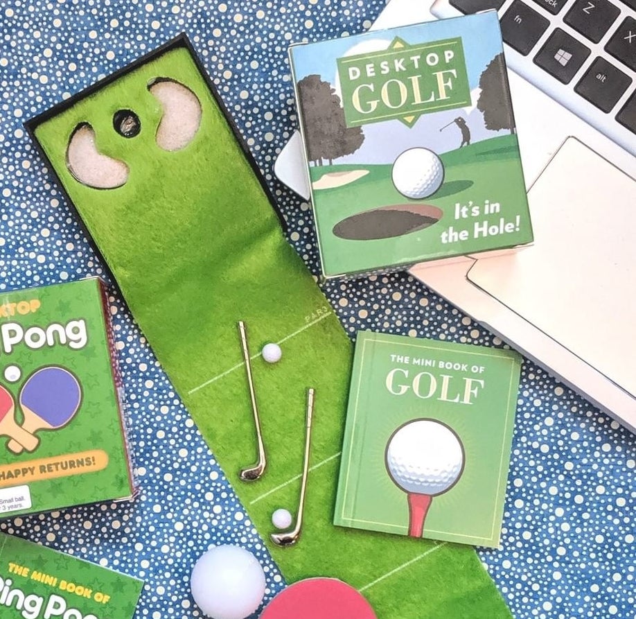 A mini golfing green with two clubs and two balls on it next to a computer