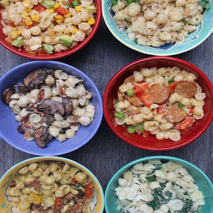 Six bowls of upgraded mac 'n' cheese with different ingredients added.