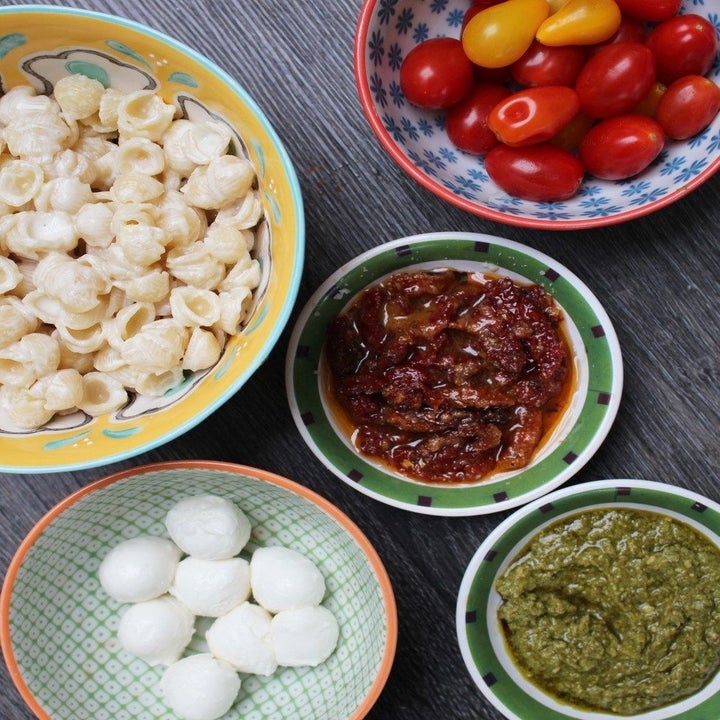 White cheddar mac 'n' cheese, tomatoes, sun dried tomatoes, pesto, and mozzarella in little bowls.