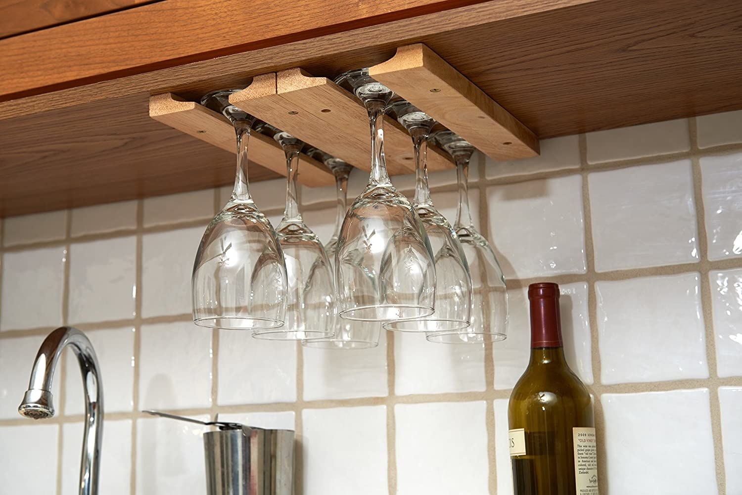 The undermounted rack containing six wine glasses in a neat kitchen