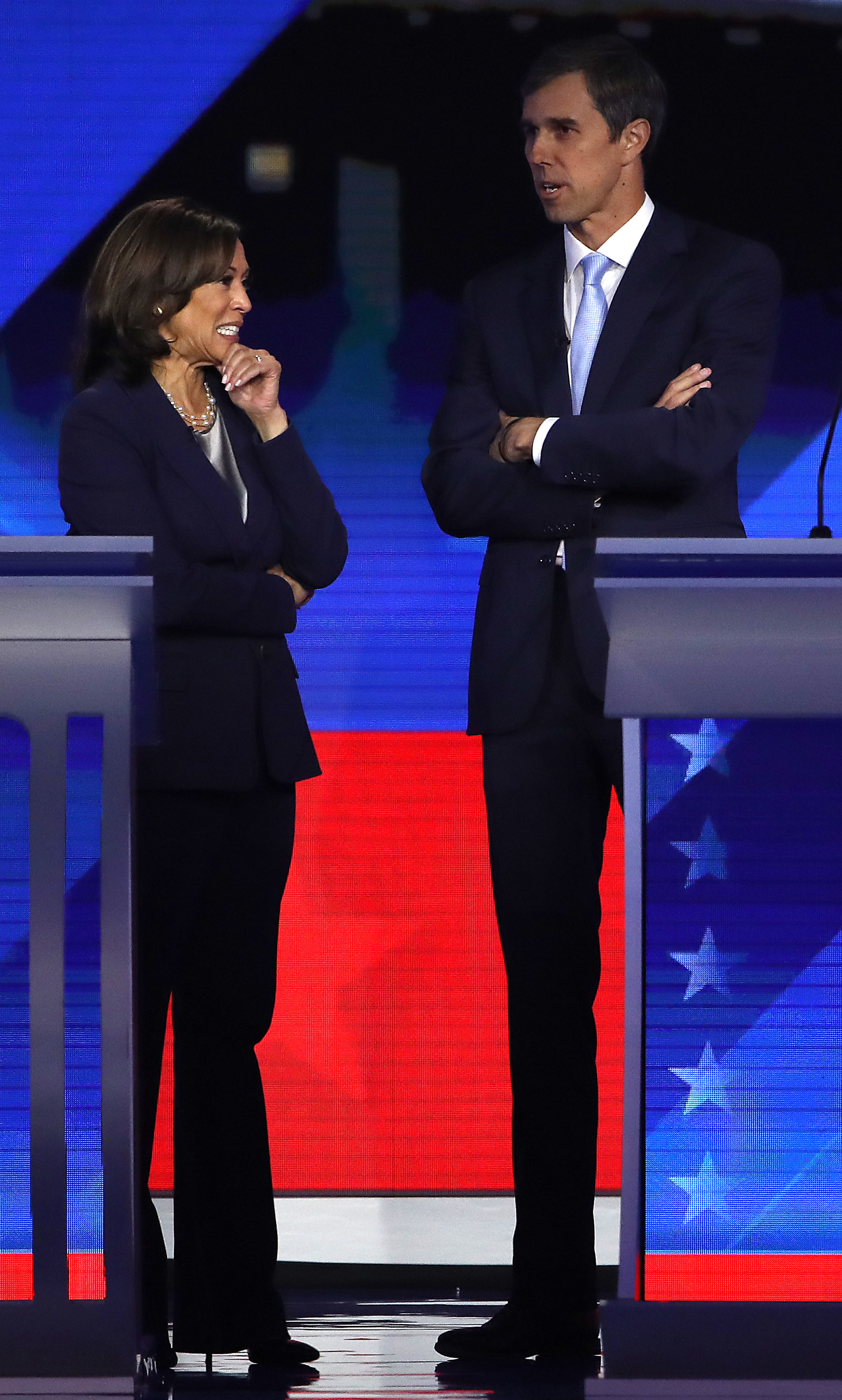 Kamala Harris, in a black pantsuit and black stiletto heels, on stage before a CNN televised debate and standing next to Beto O&#x27;Rourke.