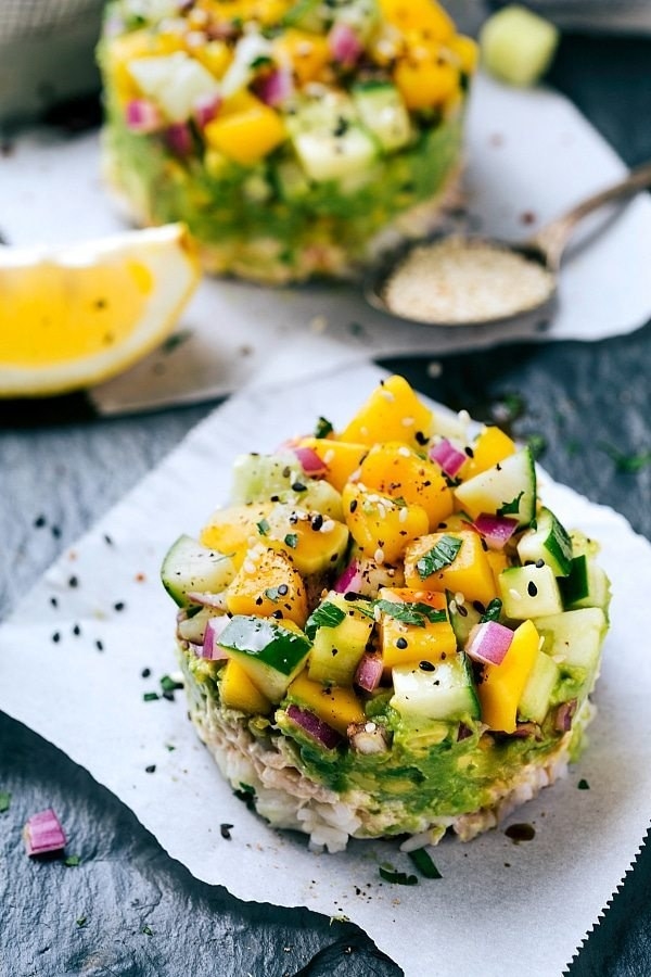 A &quot;sushi&quot; stack made with rice, canned tuna, avocado, mango, cucumer, red onion, and sesame seeds.