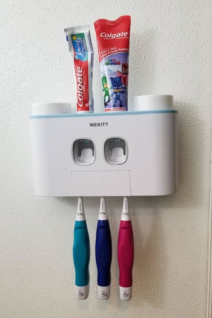 reviewer&#x27;s toothpaste dispenser, which holds two tubes on toothpaste and has three toothbrushes in it