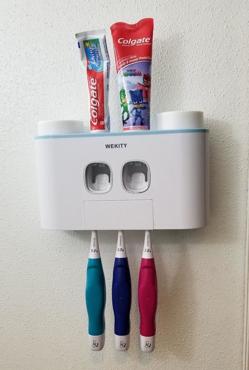 reviewer&#x27;s toothpaste dispenser, which holds two tubes on toothpaste and has three toothbrushes in it