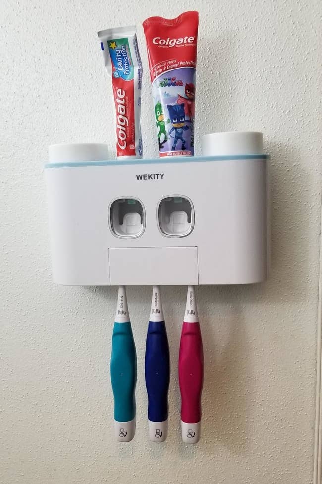 reviewer's toothpaste dispenser, which holds two tubes on toothpaste and has three toothbrushes in it