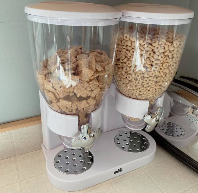 reviewer's white and clear cereal dispenser with silver knobs on their kitchen counter  