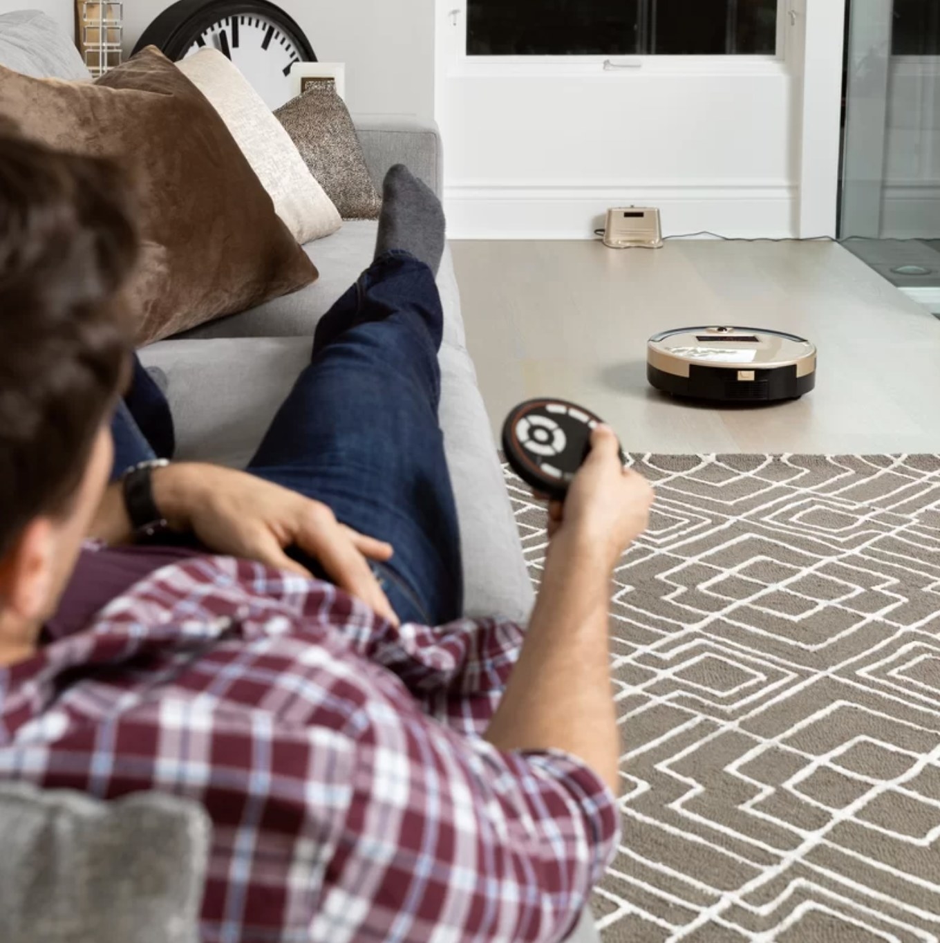 The bObsweep being controlled by a man laying on the couch