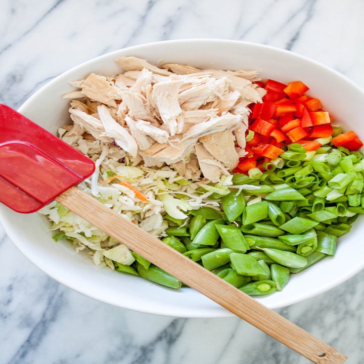 A salad with ramen, shredded chicken, cabbage, snap peas, pepper, and scallion.