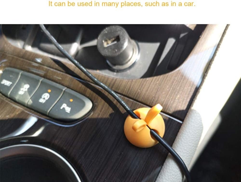 orange cable clip with bunny ears on the console holding a charging cable in place