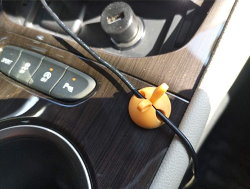 orange cable clip with bunny ears on the console holding a charging cable in place