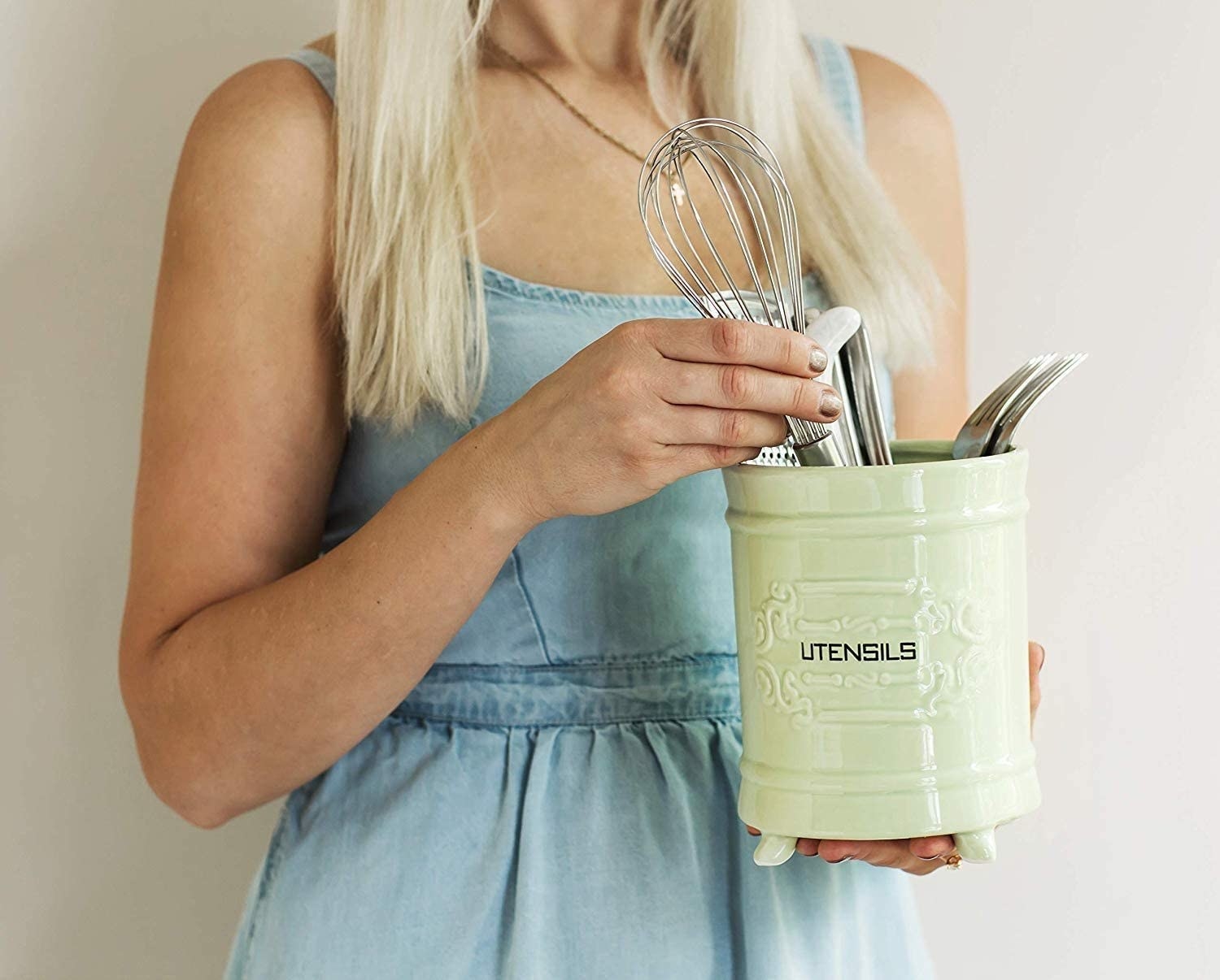 A person holds the ceramic utensil holder in front of them