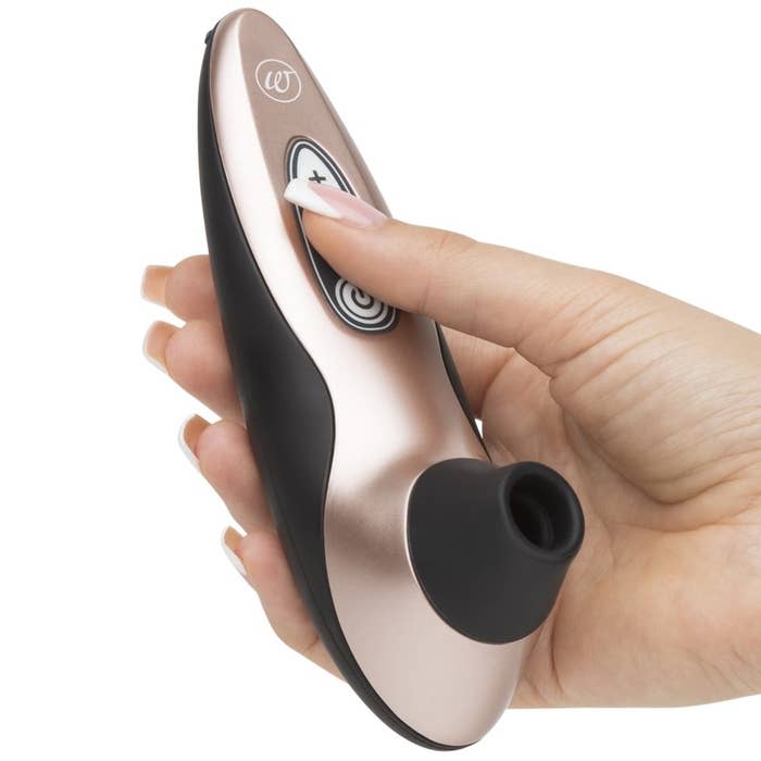 A model holding the black and pink Womanizer suction toy