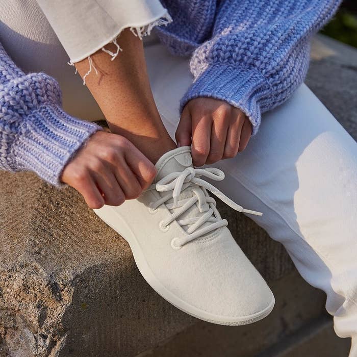 model wearing white lace-up sneakers 