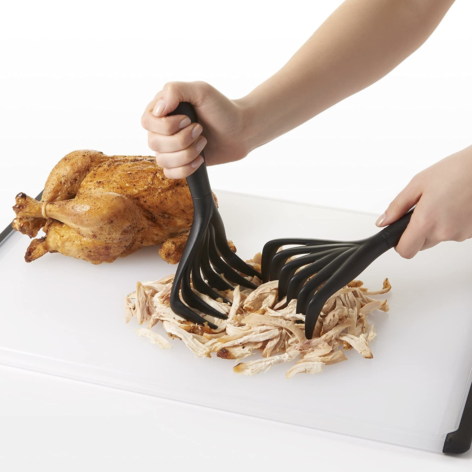 model&#x27;s hands shredding chicken with the shredders which look a lot like thick plastic rakes for food