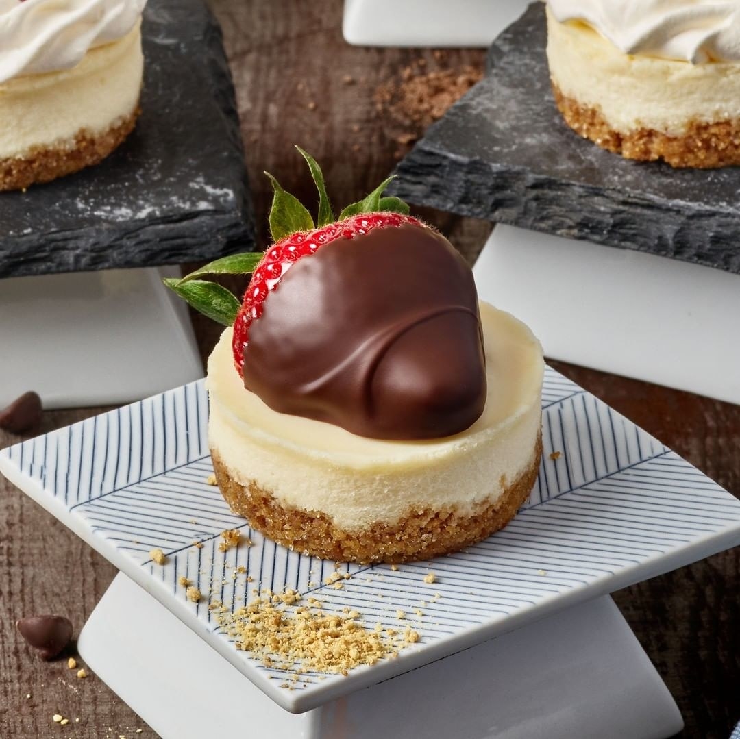 A mini cheesecake topped with a chocolate dripped strawberry