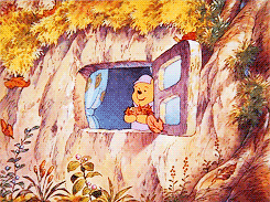 a gif of winnie the pooh holding autumn leaves while looking out his window
