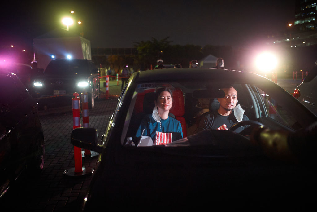 A couple at a drive-in movie wearing face masks