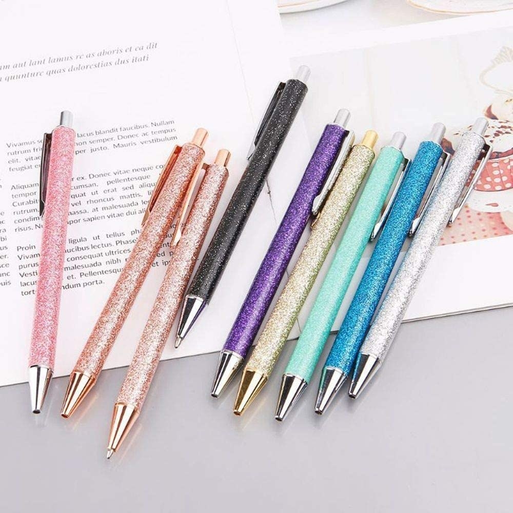 Several glittery pens laid out over a magazine