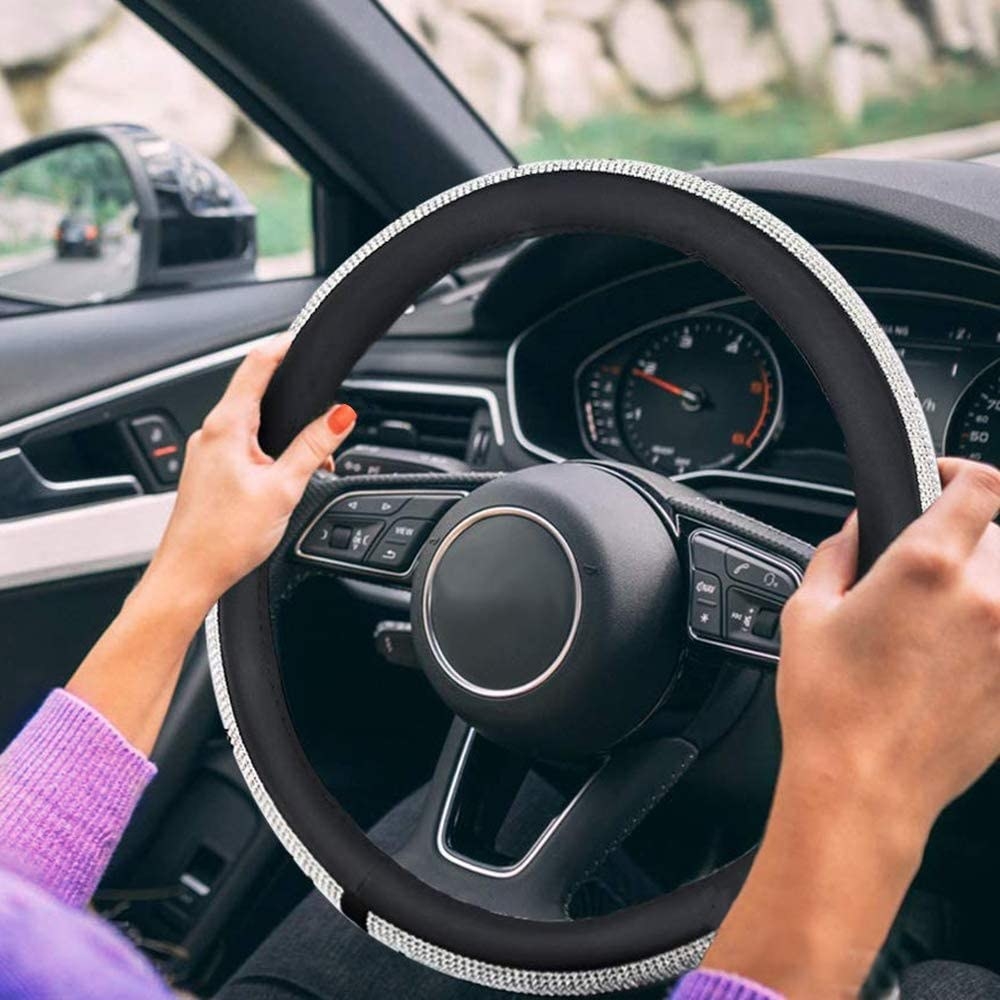 A person holding onto the bedazzled steering wheel cover