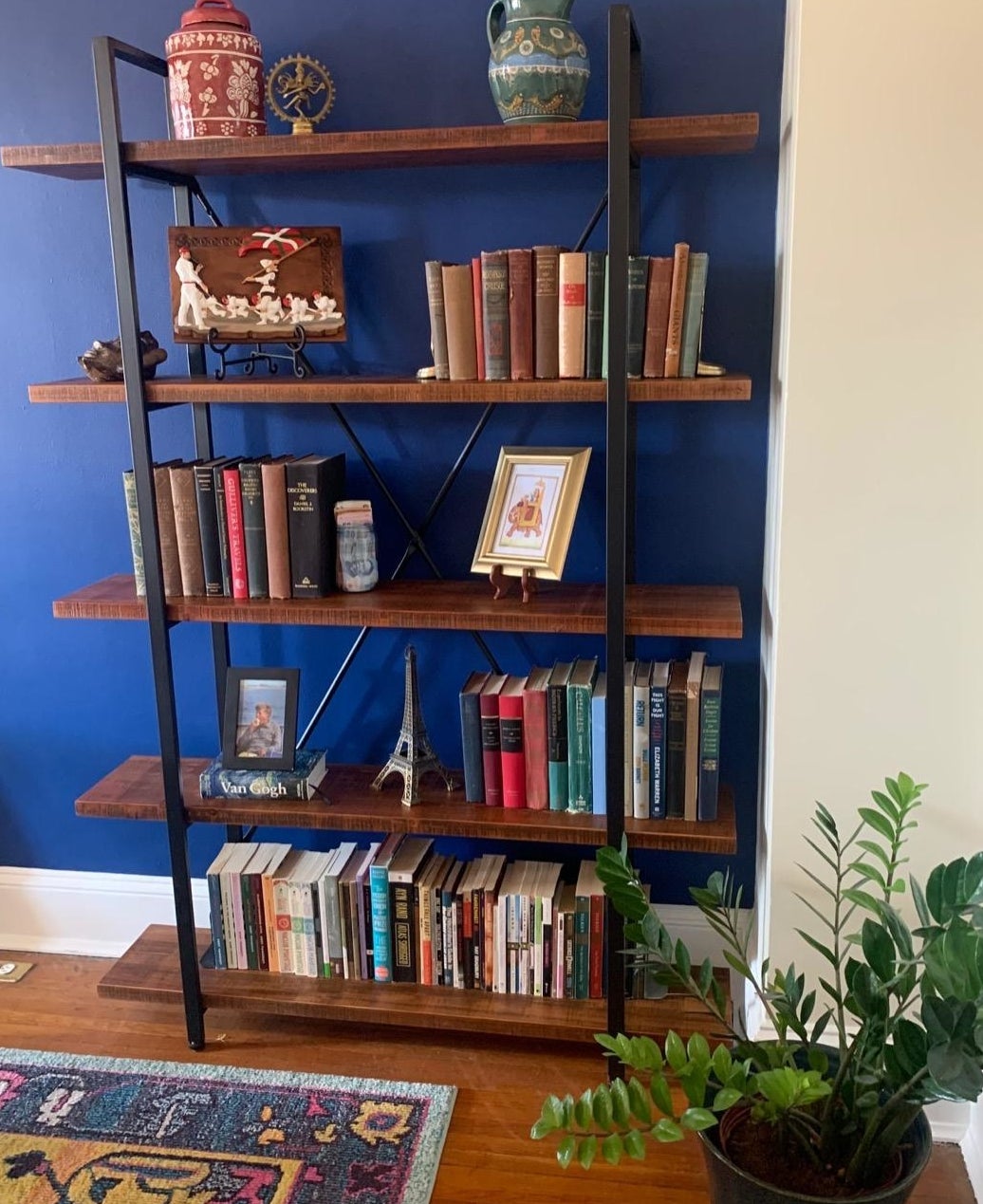 Reviewer pic of the five-shelf bookcase with books, pictures, and other trinkets on each shelf. 