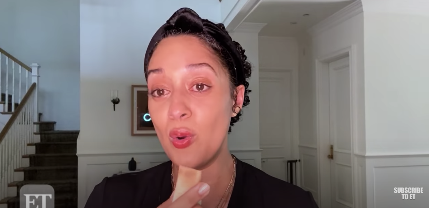 Tia Mowry speaks into a camera holding a makeup sponge