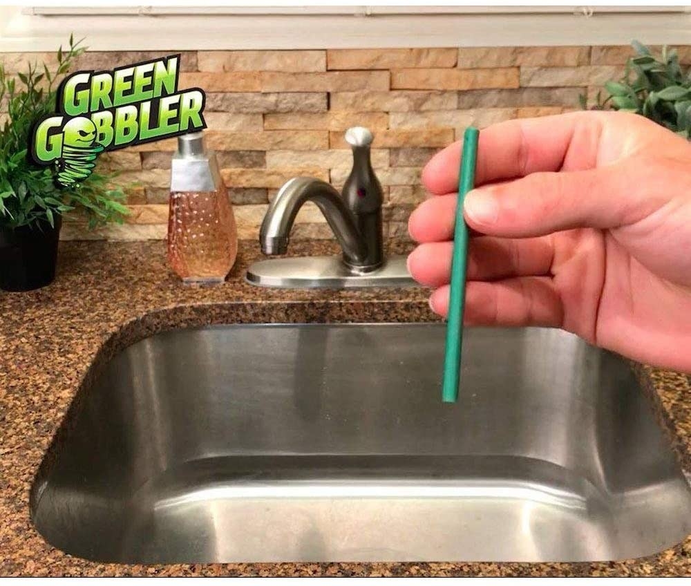 hand holds green stick near sink