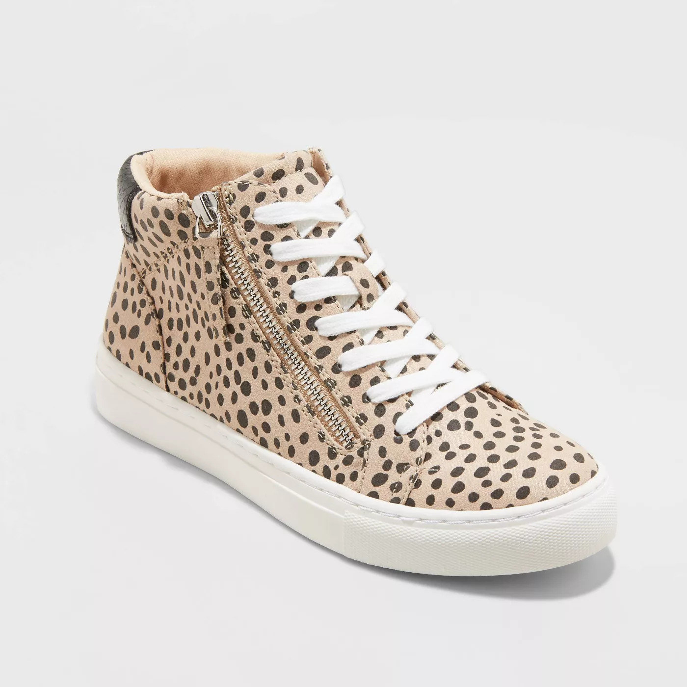 beige high top sneakers with black spots, white laces, and a zipper
