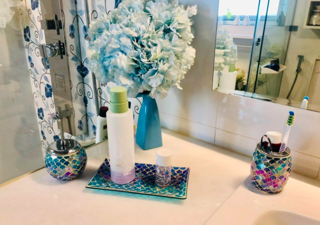 Reviewer&#x27;s shimmery pink, blue, and green bathroom accessories set on a white counter
