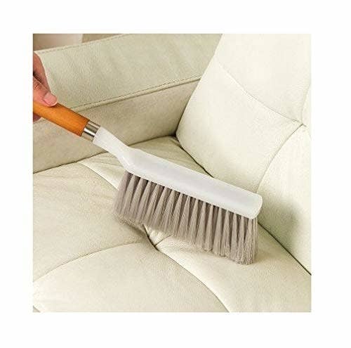 Upholstery brush being used to clean a couch.