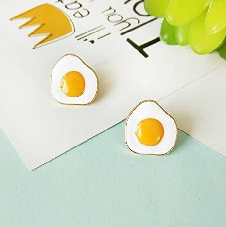 The gold-rimmed earrings shaped like sunny side up eggs