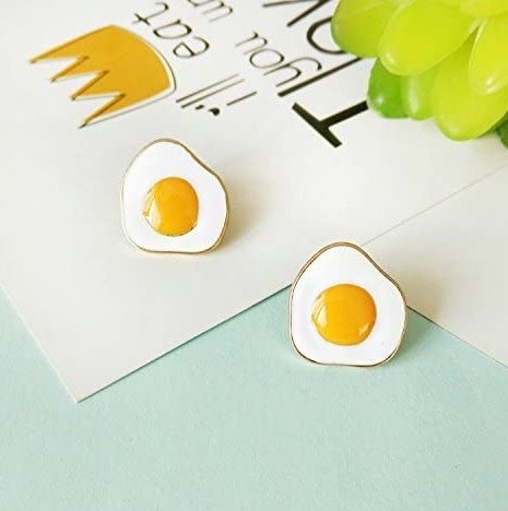 The gold-rimmed earrings shaped like sunny side up eggs