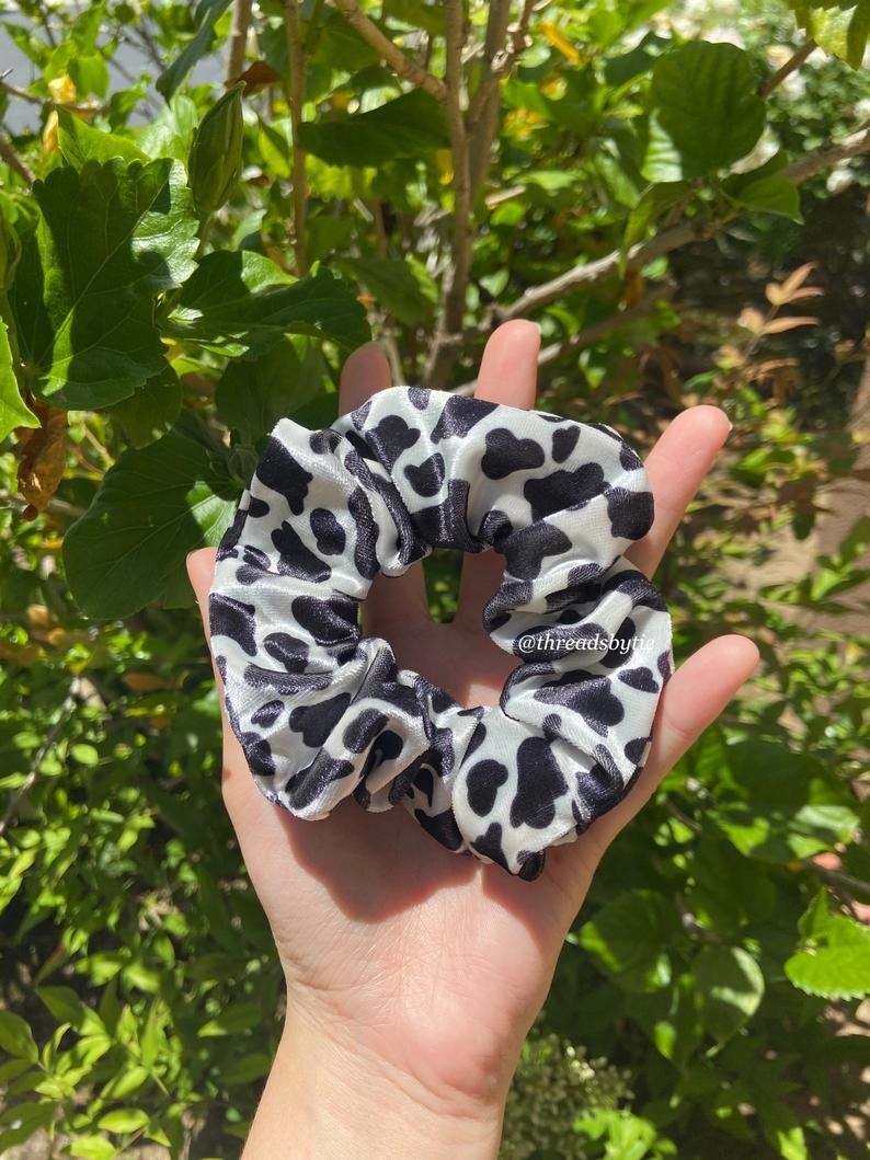 A hand holding the large black and white scrunchie