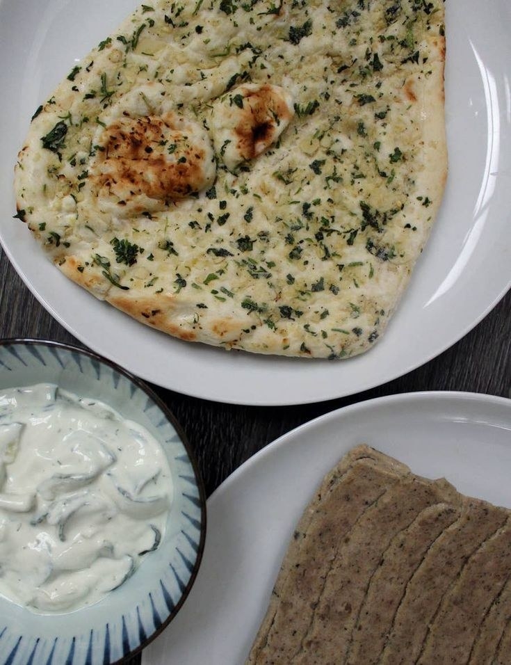 Garlic naan, a bowl of tzatziki, and a plate of sliced gyro.