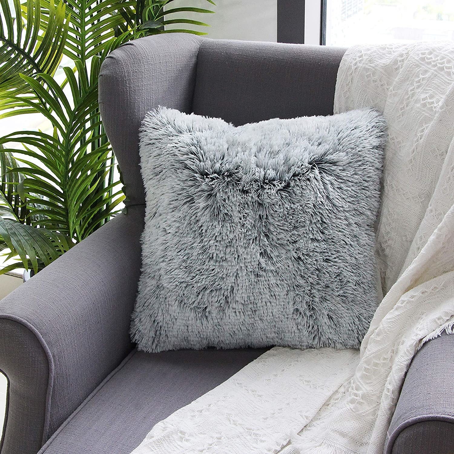 A grey faux fur square pillow on a chair 